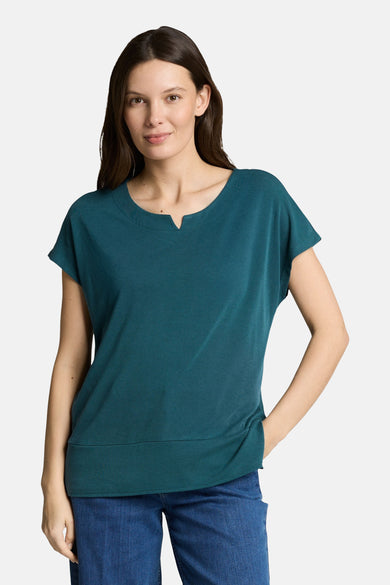 T-shirt vert à manches courtes par Tom Tailor, col rond avec ouverture en V, porté avec un jean.
