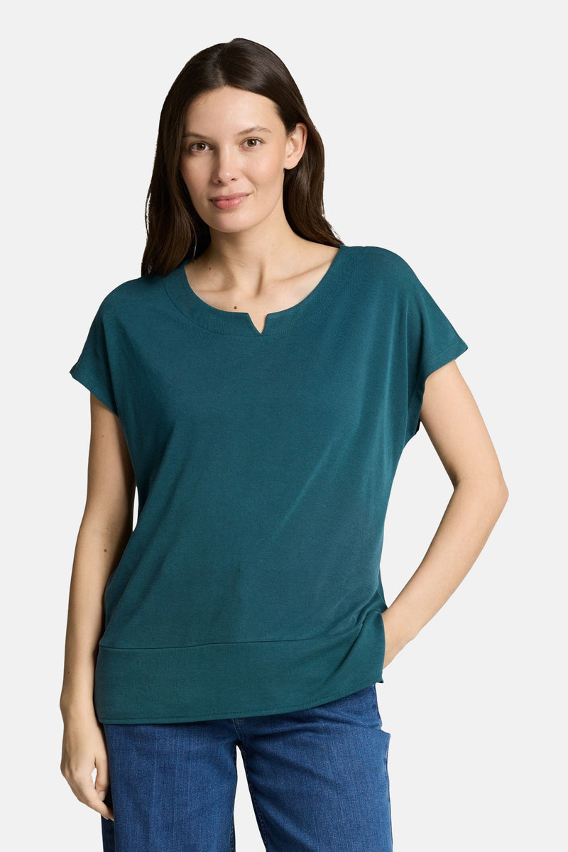 T-shirt vert à manches courtes par Tom Tailor, col rond avec ouverture en V, porté avec un jean.
