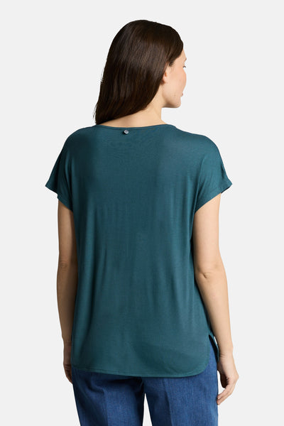 T-shirt vert à manches courtes de Tom Tailor, avec un bouton décoratif au dos et porté avec un pantalon bleu.
