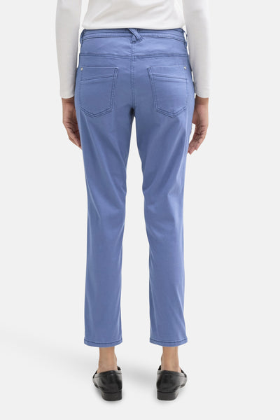 Gekleurde blauwe broek van Tom Tailor, met achterzakken, gedragen met een witte top met lange mouwen en zwarte schoenen.