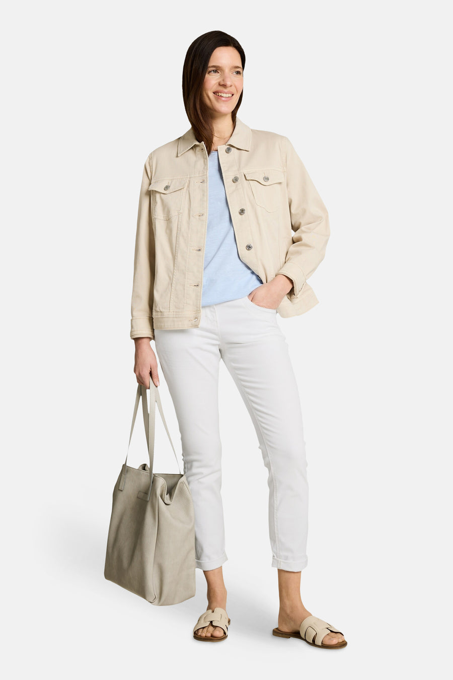 Pantalon coloré blanc de Tom Tailor, coupe droite avec revers, porté avec une veste beige, un t-shirt bleu, des sandales et un sac cabas beige.