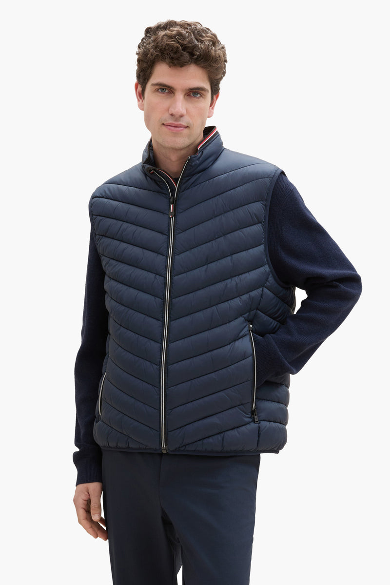 Veste sans manches bleu de Tom Tailor, matelassée avec fermeture éclair et col montant, portée sur un pull bleu.