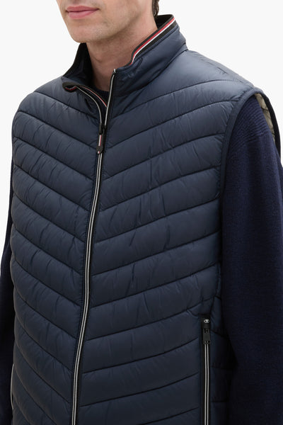 Veste sans manches bleue de Tom Tailor, matelassée avec fermeture éclair, portée sur un pull en tricot.