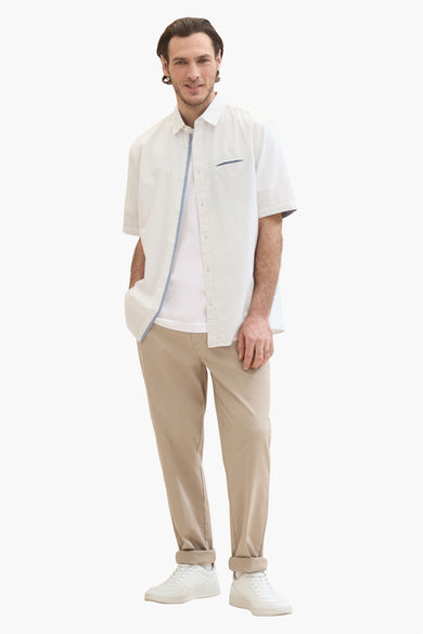 Chemise à manches courtes blanche Tom Tailor avec motif discret, portée sur un t-shirt et un pantalon beige.