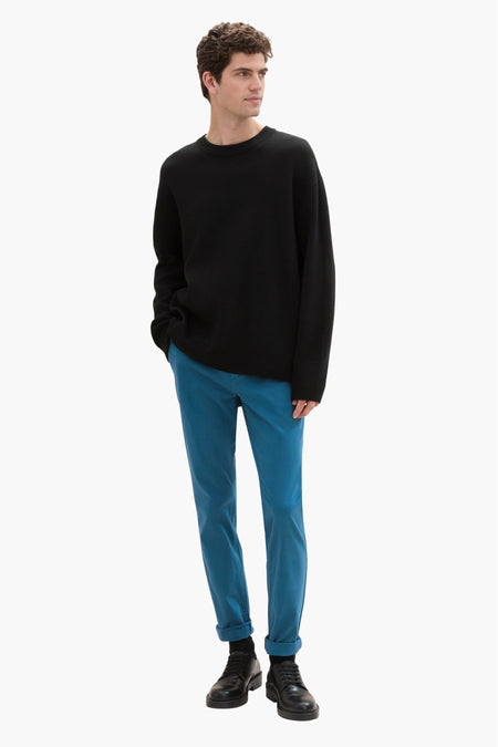 Chino vert de Tom Tailor, porté avec un pull noir ample et des chaussures en cuir.