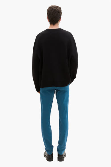 Groene chino van Tom Tailor, gedragen met een zwarte trui en zwarte schoenen, achtergezicht.