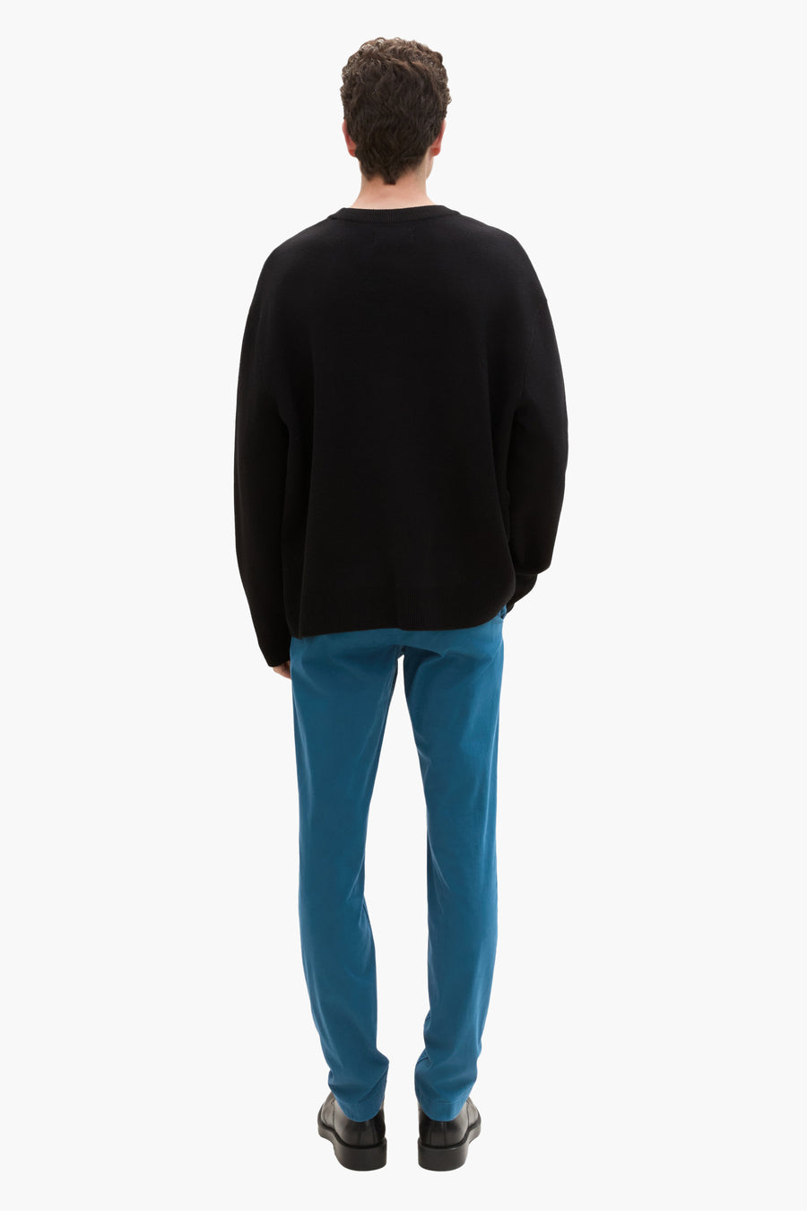 Groene chino van Tom Tailor, gedragen met een zwarte trui en zwarte schoenen, achtergezicht.