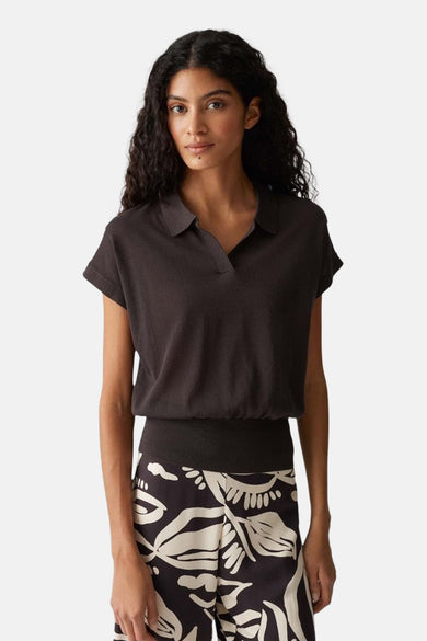 Donkerbruin poloshirt met korte mouwen van OPUS, gedragen met een zwart-crème bloemenbroek.