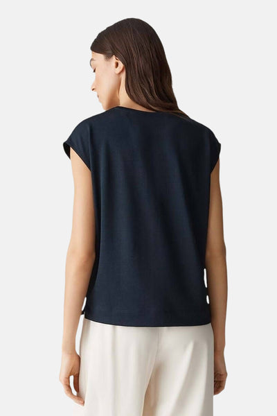 Zwart mouwloos blouse van OPUS, van achteren gezien, gedragen met een witte broek.