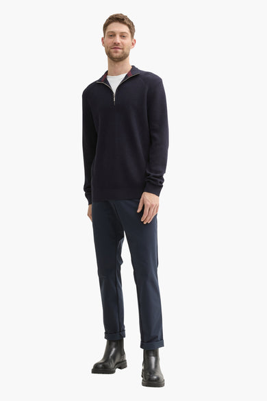 Blauwe pull van Tom Tailor, gedragen over een wit t-shirt, met een zwarte broek en zwarte laarzen.