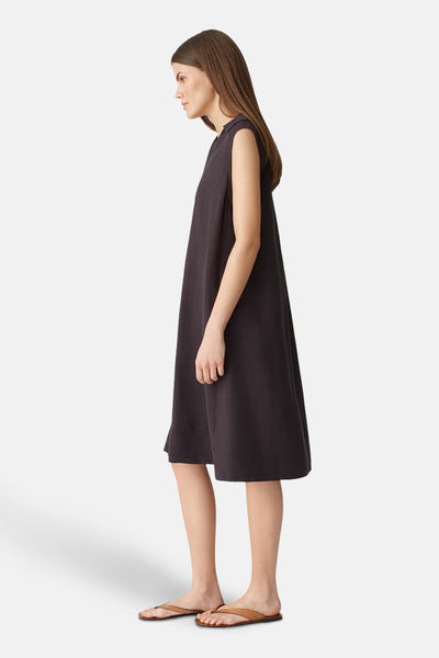 Robe brune sans manches par OPUS, coupe ample mi-longue, portée avec des sandales en cuir marron.