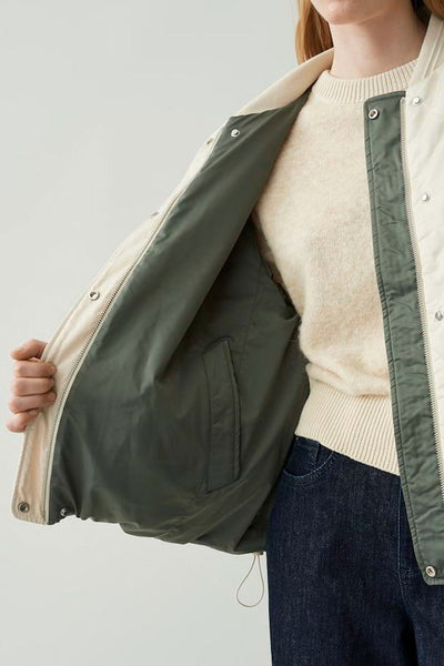 Veste courte écru de OPUS avec doublure verte, poche intérieure et fermeture à boutons pression.