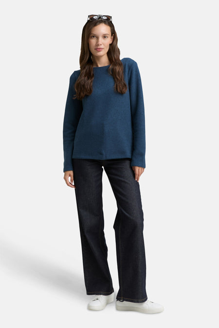 Blauwe ronde hals trui van Tom Tailor, gedragen met een wijde jeans en witte sneakers.