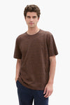 Blauw T-shirt met korte mouwen van Tom Tailor, met een man met bruin krullend haar en een marineblauwe broek.
