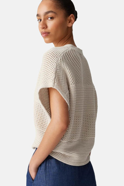 Pull écru en maille ajourée de OPUS, porté avec un pantalon bleu marine.