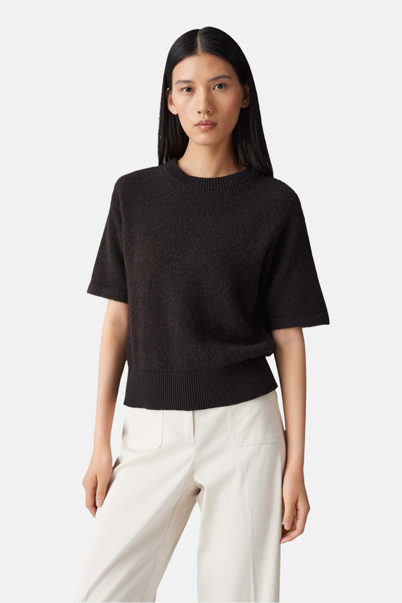 Pull brun à manches courtes par OPUS, porté avec un pantalon de couleur crème.