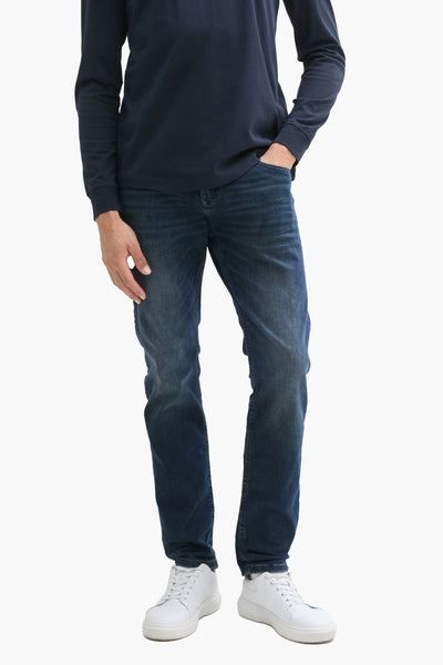 Jean droit en denim bleu foncé de Tom Tailor, porté avec un t-shirt bleu marine et des chaussures blanches.