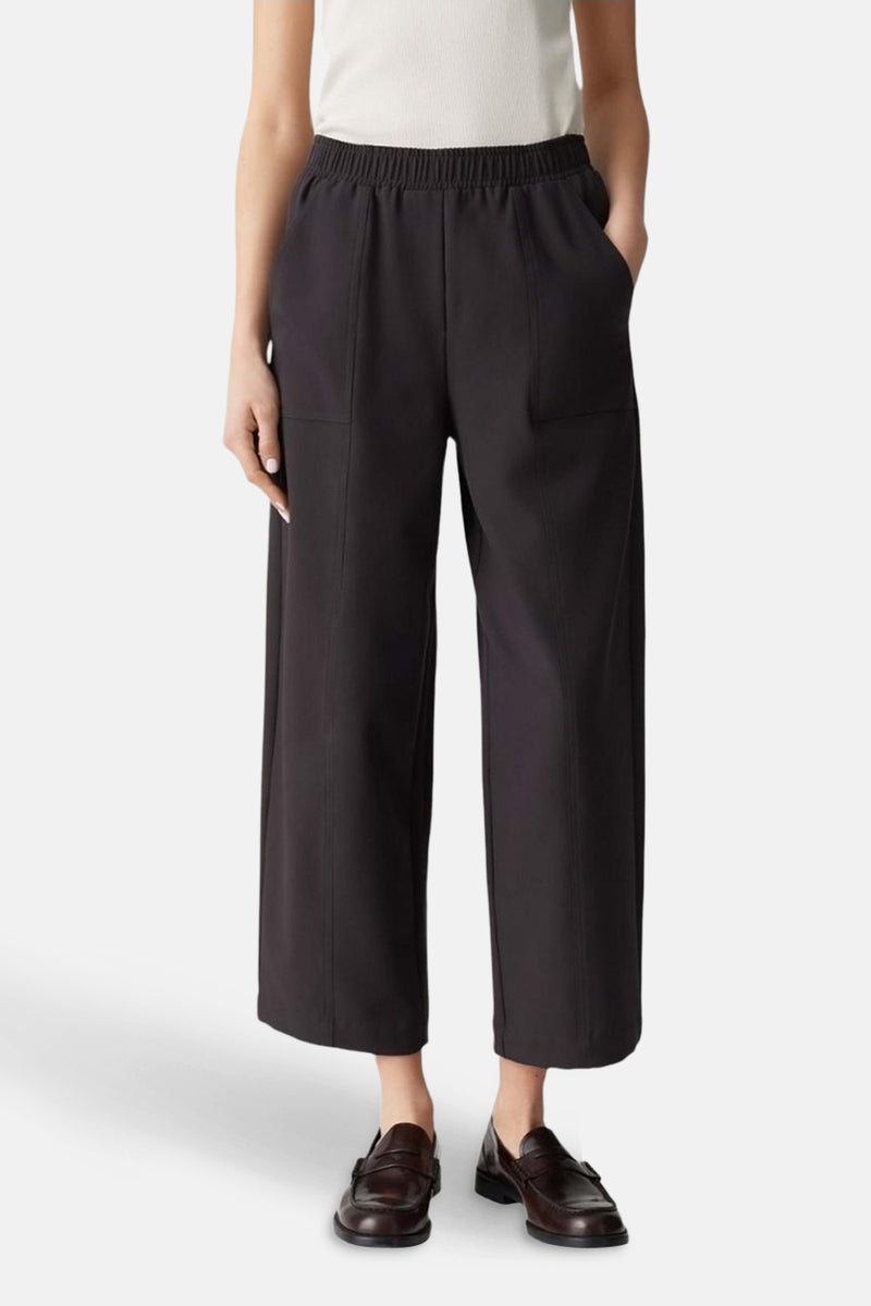 Pantalon brun par OPUS, avec une taille élastique, des poches latérales et des chaussures en cuir marron.