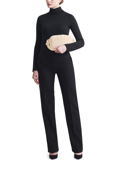 Sac à main beige par OPUS porté avec un pantalon noir et un col roulé noir.