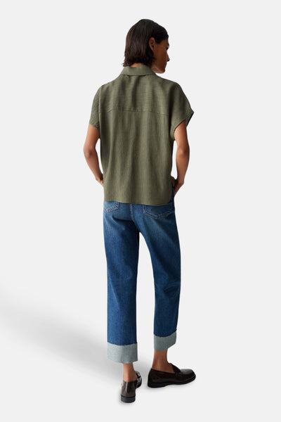 Chemise à manches courtes verte, texturée par OPUS, portée avec un jean bleu à revers et des mocassins noirs.