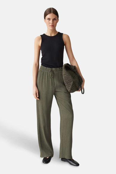 Pantalon vert en tissu texturé par OPUS, porté avec un débardeur noir et des ballerines noires.