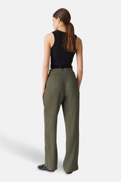 Pantalon vert de OPUS, avec une texture plissée, porté avec un débardeur noir et des chaussures plates noires.