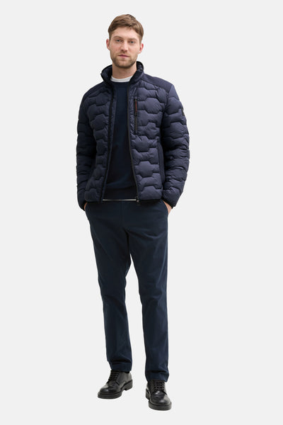 Veste courte bleue de Tom Tailor, matelassée avec fermeture éclair, portée avec un pull et un pantalon bleu marine.