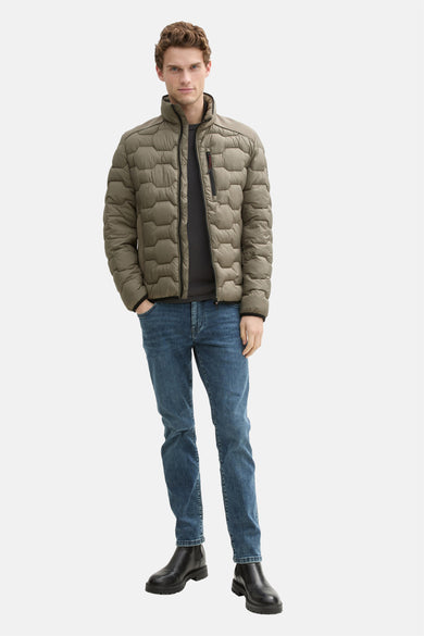 Veste courte kaki par Tom Tailor, avec motif hexagonal et porté avec un jean bleu et des bottes noires.