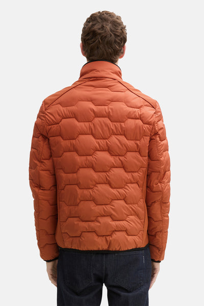 Veste courte orange par Tom Tailor, avec motif hexagonale et texture matelassée visible de dos.