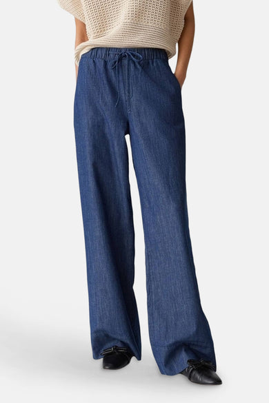 Pantalon en denim bleu moyen par OPUS, coupe ample, cordon de serrage à la taille et chaussures noires.
