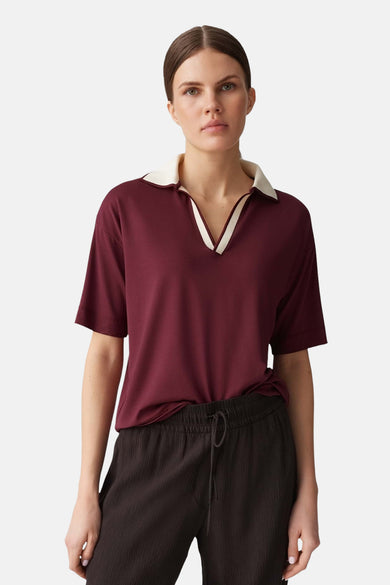 Pull bordeaux de OPUS, à col polo blanc, porté avec un pantalon ample marron à cordon.
