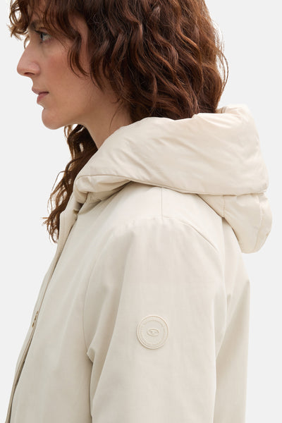 Korte beige jas van Tom Tailor, met gewatteerde capuchon en rond logo op de mouw.