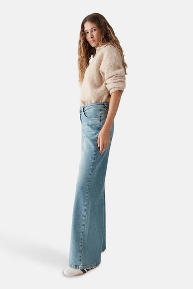 Jean droit en denim bleu clair de OPUS, porté avec un pull beige en maille duveteuse.
