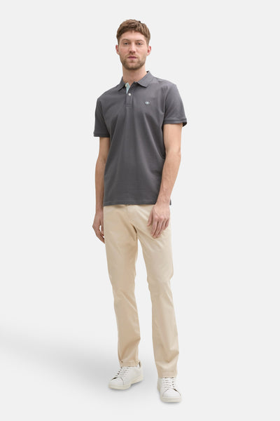 Pantalon coloré beige de Tom Tailor, porté avec un polo gris et des baskets blanches.