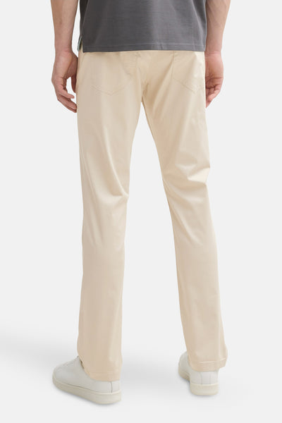 Pantalon coloré beige de Tom Tailor, avec des poches arrière et des baskets blanches.