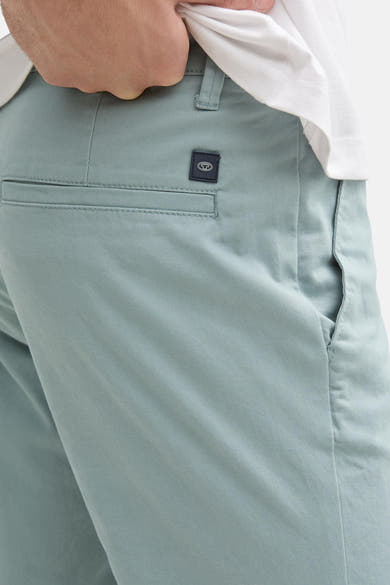 Grijze chino van Tom Tailor, met paspelzak achter en logodetail, gedragen met een wit T-shirt.