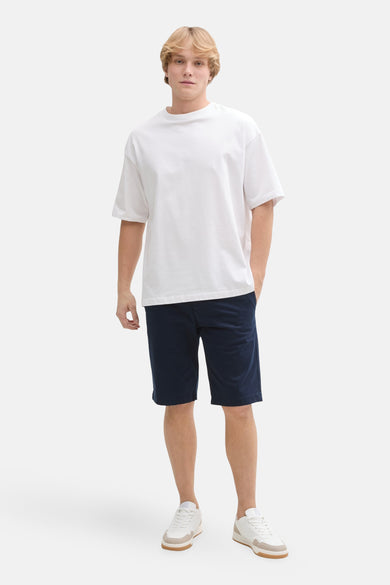 Short bleu de Tom Tailor, porté avec un t-shirt blanc et des baskets blanches et beiges.