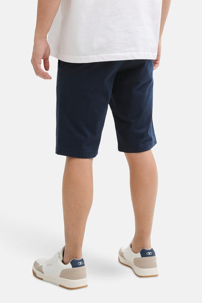 Short bleu marine de Tom Tailor, porté avec un t-shirt blanc et des baskets blanches et beige, vue de dos.
