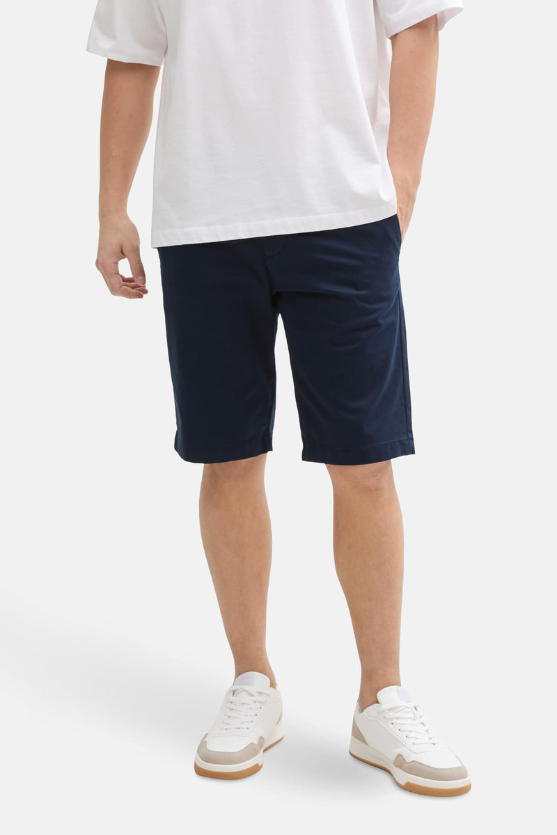 Short bleu de Tom Tailor, porté avec un t-shirt blanc et des chaussures de sport blanches et beiges.