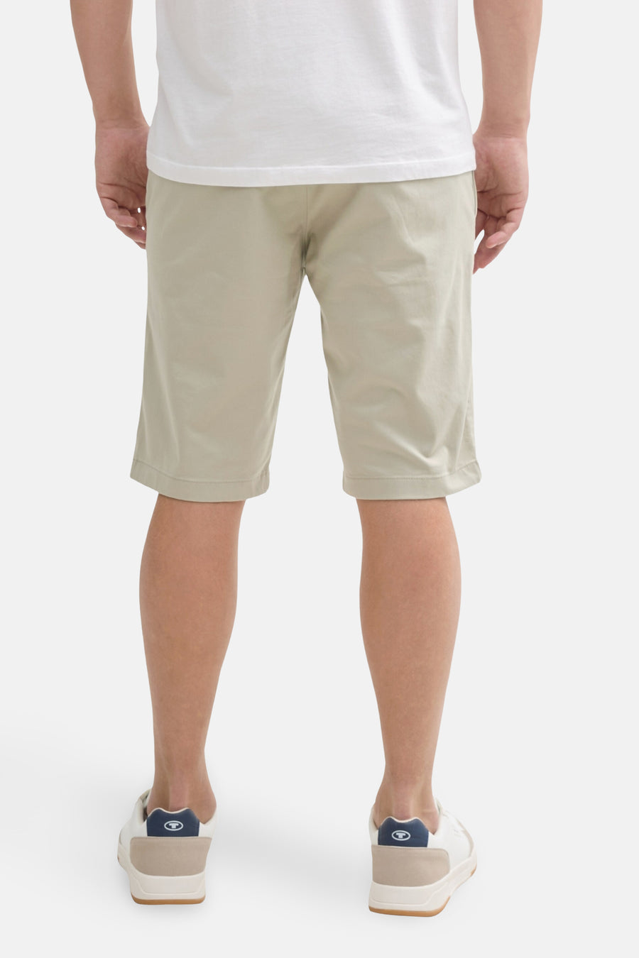 Korte beige broek van Tom Tailor, gedragen met een wit T-shirt en crèmekleurige lage sneakers, van achteren gezien.