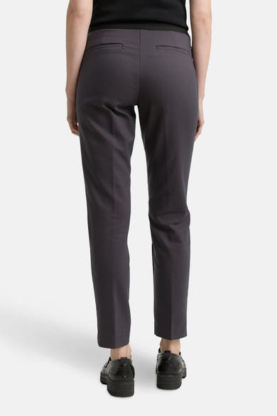 Grijze broek van Tom Tailor, met paspelzakken achter, gedragen met zwarte schoenen met dikke zolen.