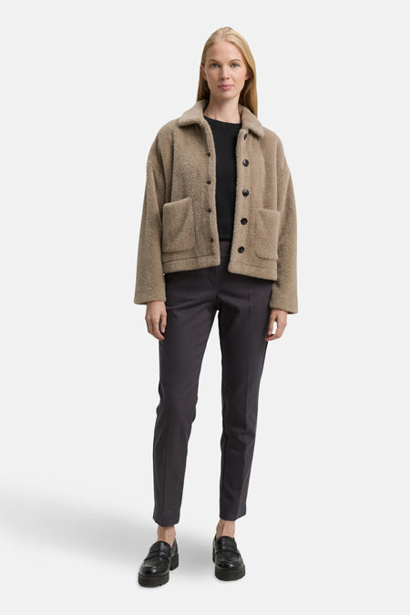 Grijze broek van Tom Tailor, gedragen met een zwarte trui en een bruine wollen jas.