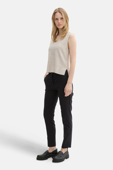 Zwarte broek van Tom Tailor, gedragen met een beige mouwloze trui en zwarte lage schoenen.