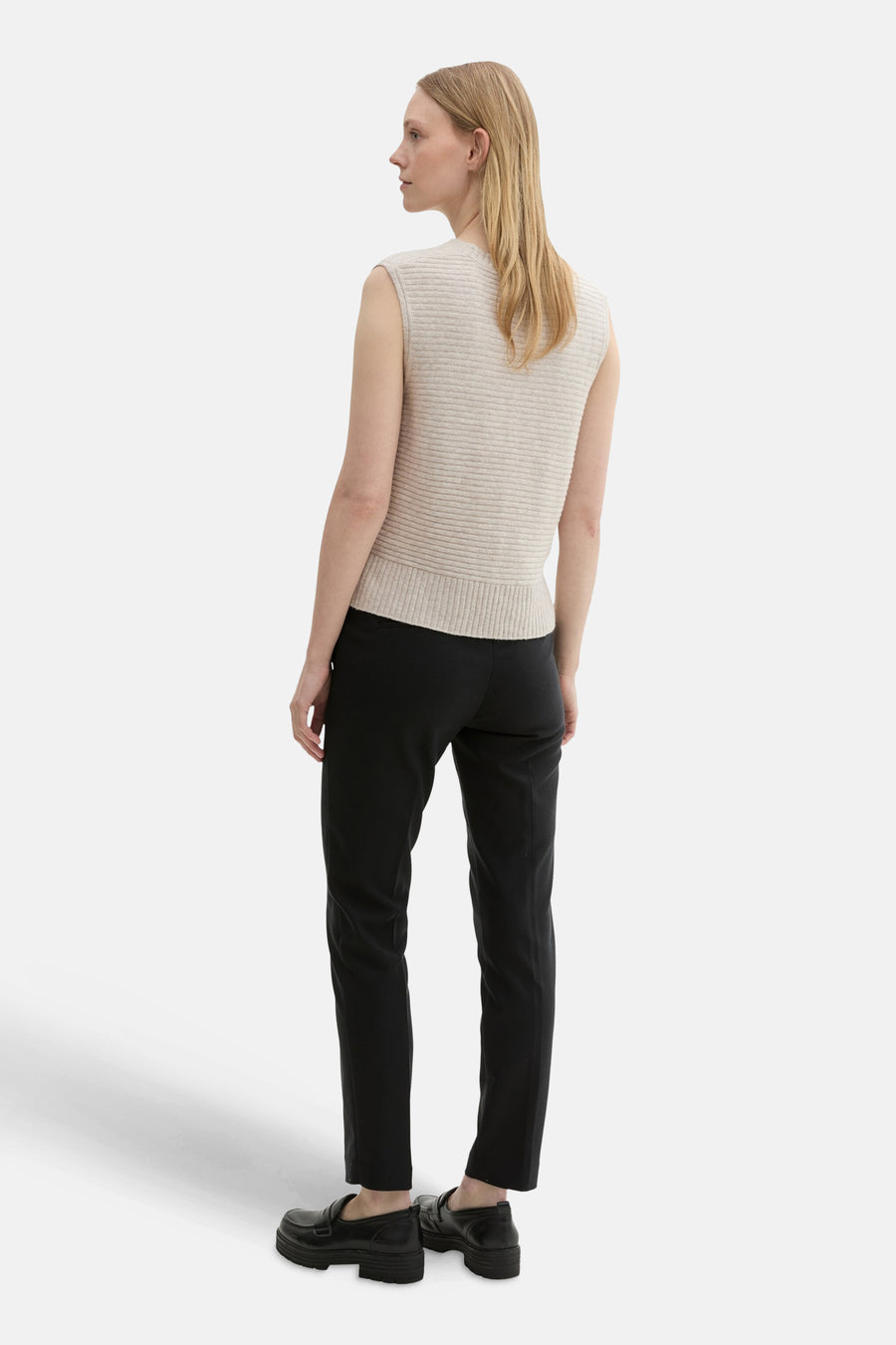 Zwarte broek van Tom Tailor, rechte pasvorm, gedragen met een beige mouwloze gebreide top en zwarte loafers.