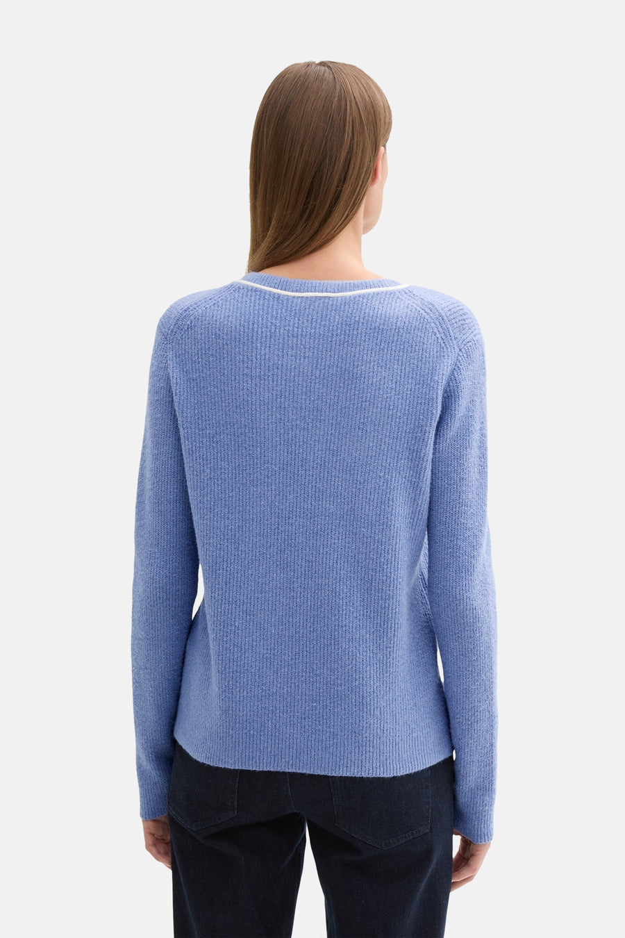 Ronde hals trui blauw van Tom Tailor, met witte rand bij de hals en gebreide textuur, gedragen met een donkere broek.