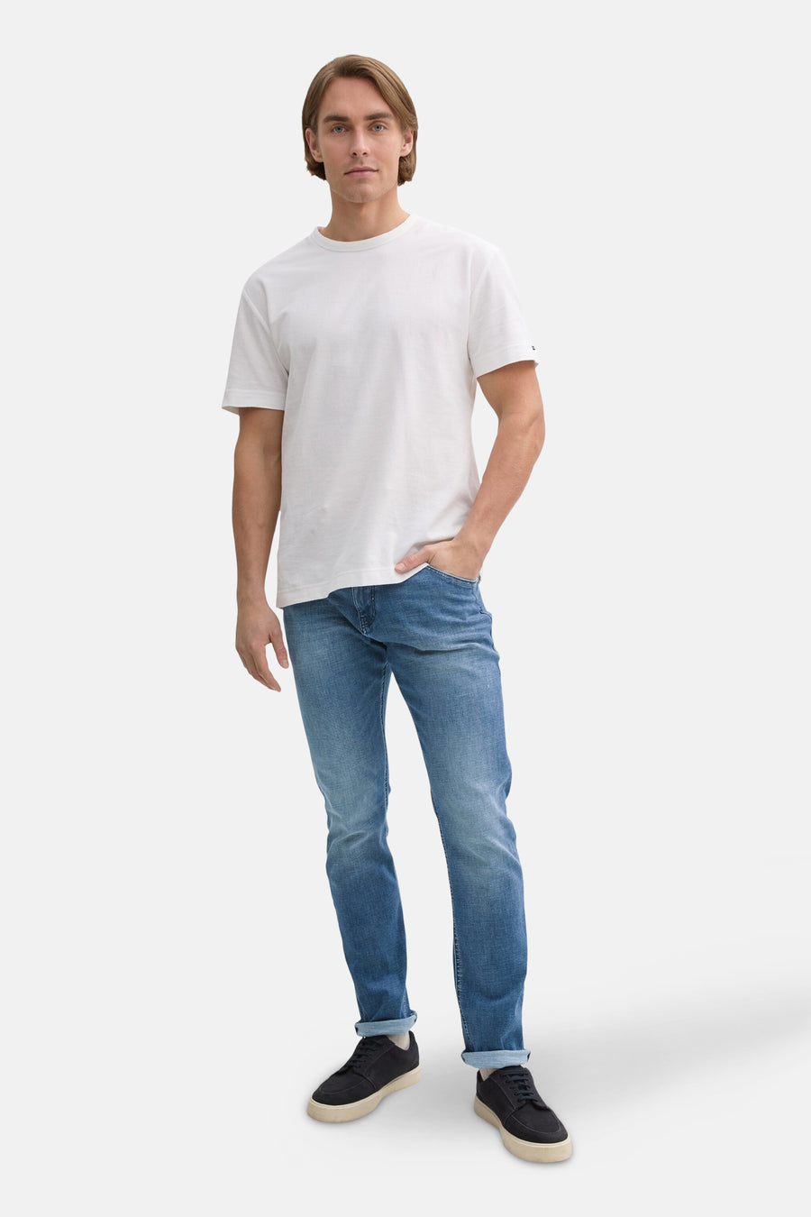 Jean slim en denim bleu moyen de Tom Tailor, porté avec un t-shirt blanc et des chaussures noires.

