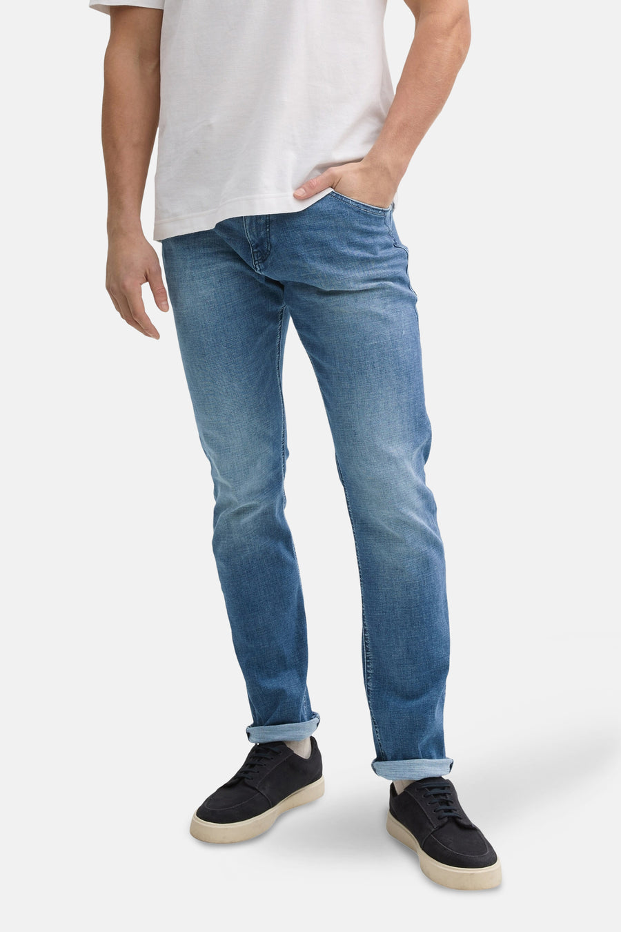 Slim jeans in medium blue denim van Tom Tailor, gedragen met een wit T-shirt en zwarte schoenen.