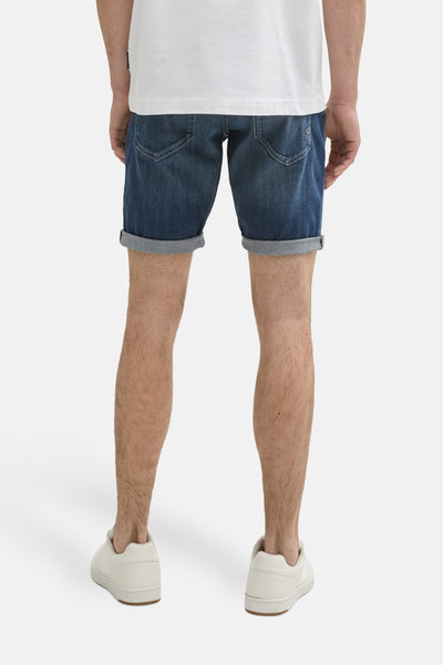Short en denim bleu foncé de Tom Tailor, avec ourlet retroussé, porté avec un t-shirt blanc et des baskets blanches.
