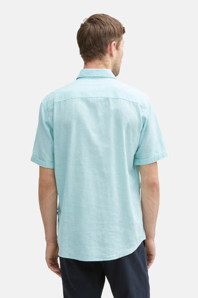 Chemise turquoise à manches courtes de Tom Tailor, vue de dos, sur un pantalon bleu marine.