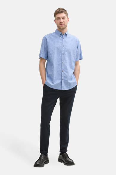 Chemise bleue à manches courtes de Tom Tailor, portée avec un pantalon noir et des chaussures en cuir.